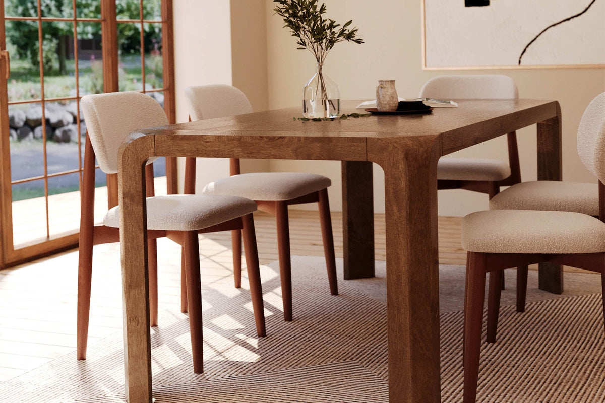 Tristan brown mango wood dining table with cream chairs in a sunlit room with arched windows