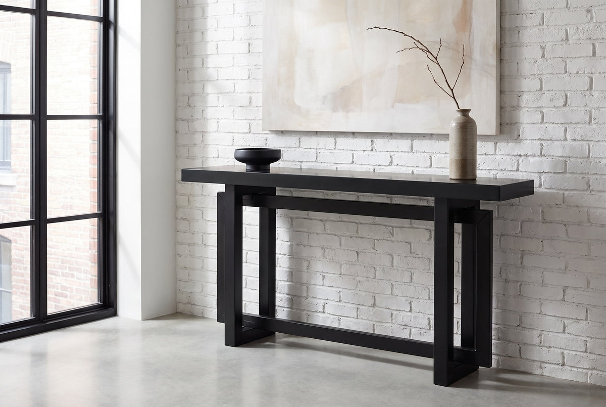 Urbania console table against a whitewashed brick wall in a loft entry, a branch in a stoneware vase