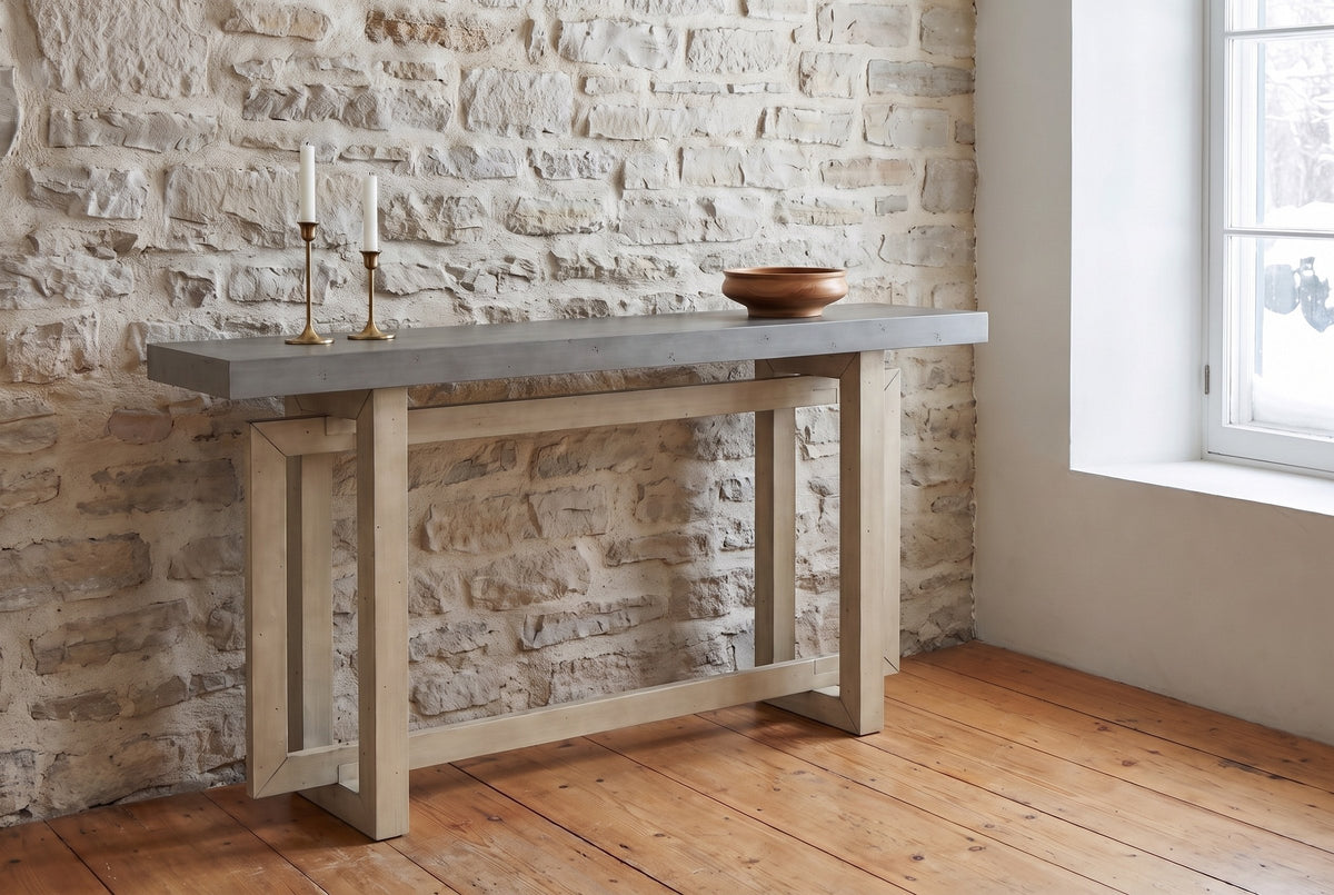 Urbania console table in Gray against an old limestone wall, brass candlesticks and a wooden bowl on top