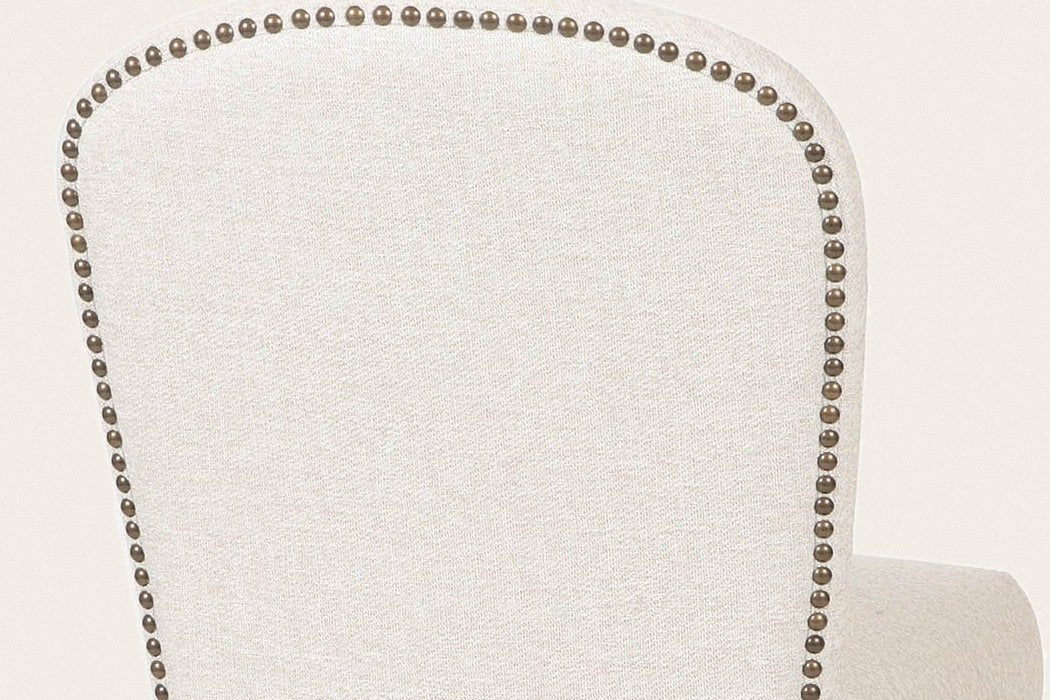 Close-up of the back of the Usseglio dining chair: one row of antique-bronze nailheads round the arched top of the cream woven back