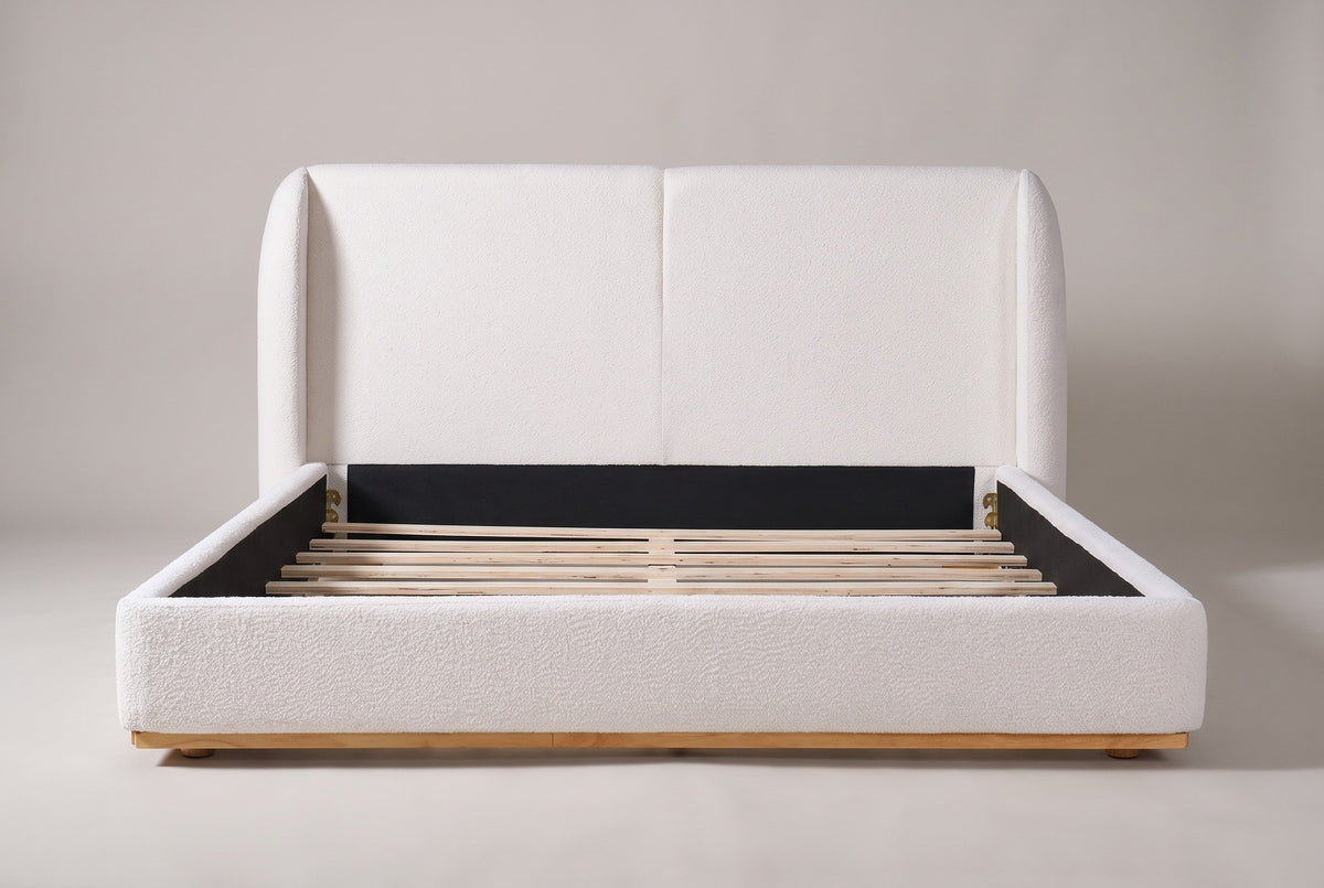 Varenna bed seen straight on from the foot: a two-panel headboard between two rounded wings