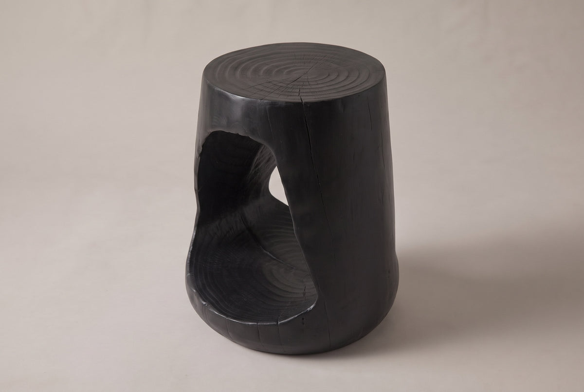 Venzone side table in Black, three-quarter view on a warm grey studio backdrop, the opening on its left side