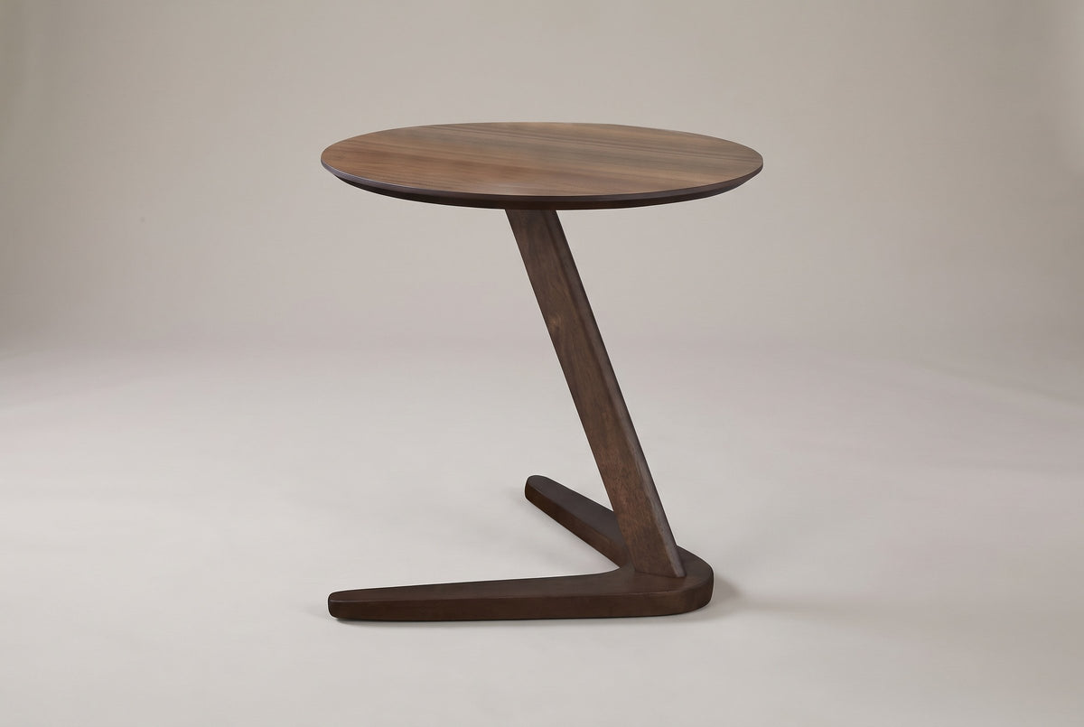 Vigevano side table in walnut, front view: the post leans from the corner of the base up to the middle of the round top