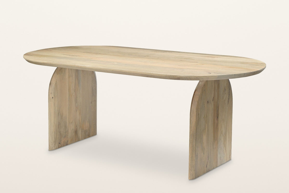 Visso dining table in Natural, three-quarter view on a warm white studio backdrop: pale mango top with round ends on two arch