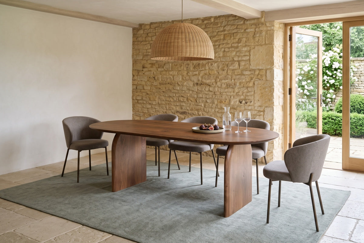 Visso dining table in Pecan in a dining room with a honey stone wall