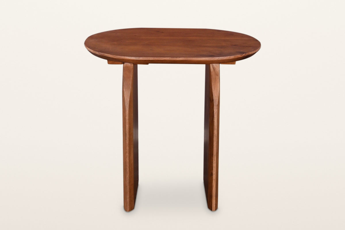 Visso side table in Pecan from the long side, on a warm white studio backdrop: the oval top