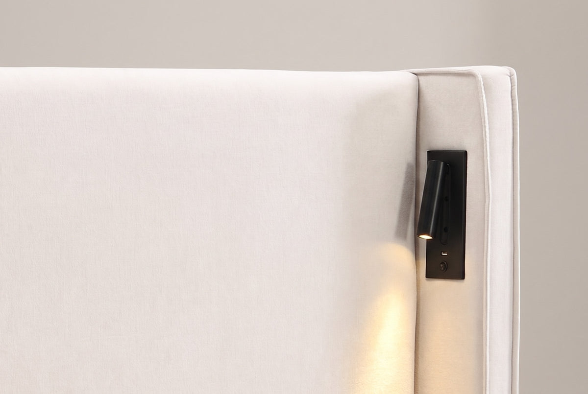 Close-up of a Viterbo reading lamp on the inside of the wing: black plate, swing arm, warm LED, USB port and switch