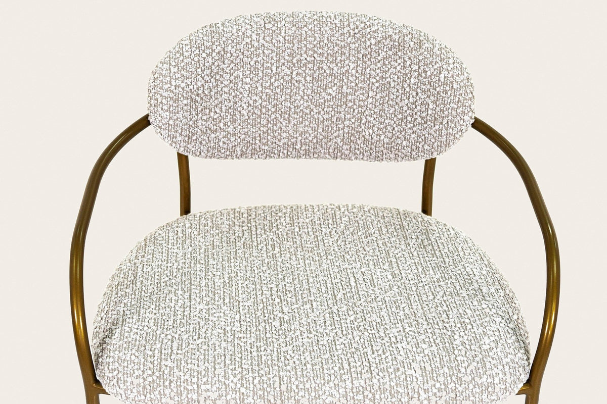 Close-up of the Vitorchiano counter stool from above: the Pearl Grey bouclé back pad and seat, the antique bronze arms curving round the seat