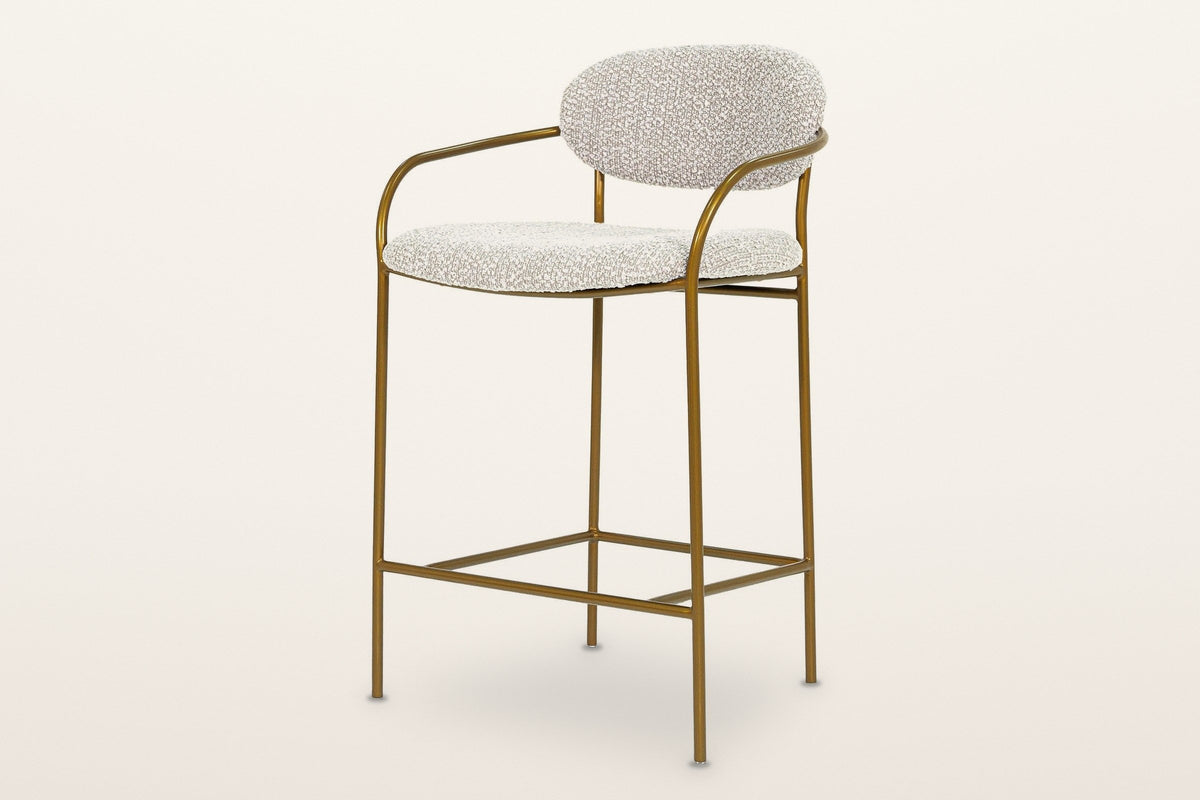 Vitorchiano arm counter stool in Pearl Grey bouclé on a slim antique bronze tube frame: an oval back pad, two bent-tube arms, four straight legs and a footrest frame, three-quarter view on a warm white studio backdrop