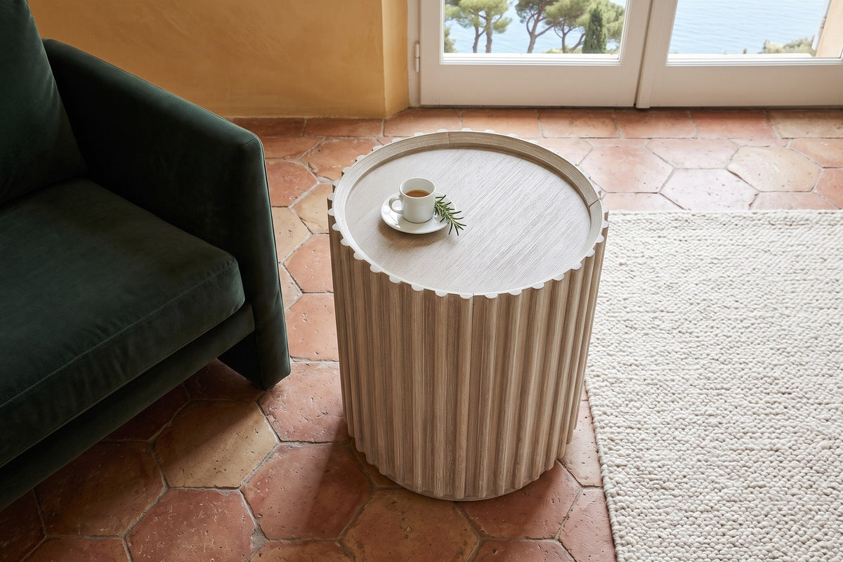 The Vitorchiano side table in Natural White Washed seen from above beside a green velvet lounge chair in a cliff villa