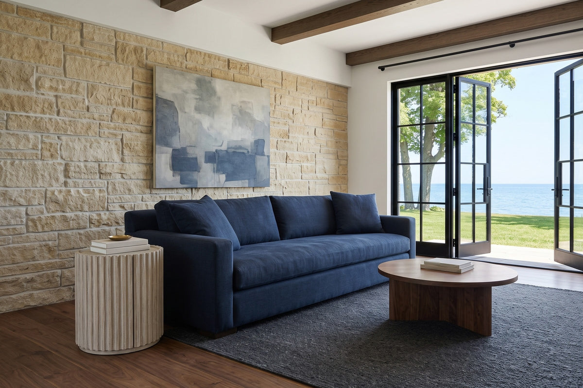Vitorchiano side table in Natural White Washed at the arm of a navy linen sofa in a Port Stanley house, with a limestone wall