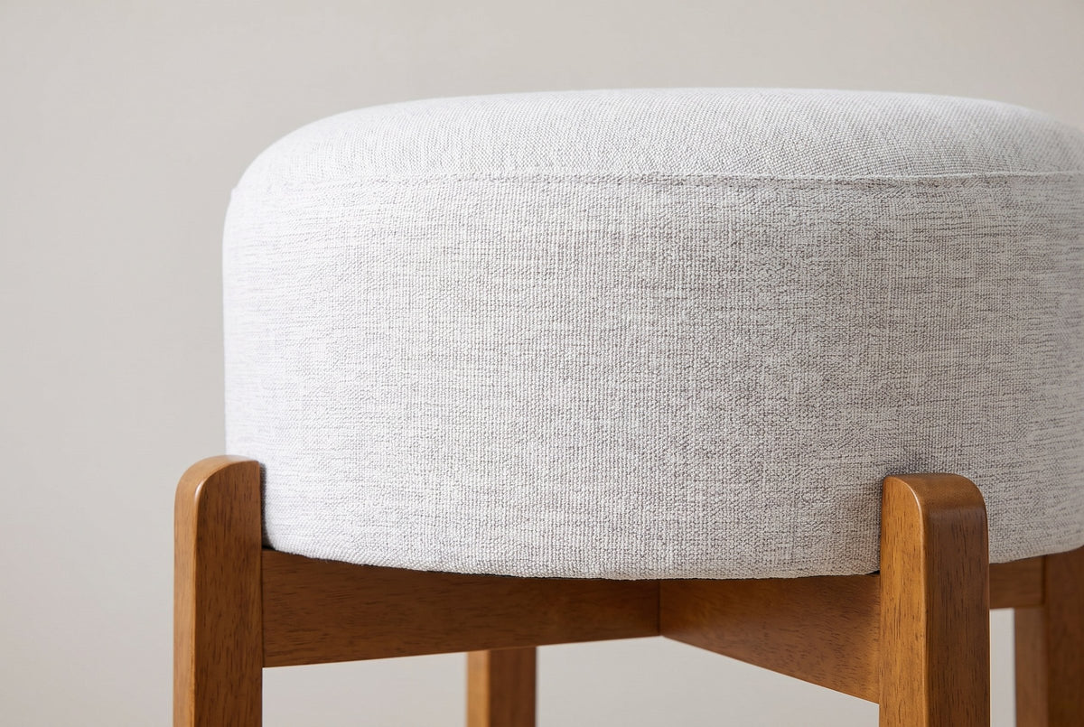 Close-up of the Vogogna ivory linen-look drum cushion held in the notched tops of the Walnut legs