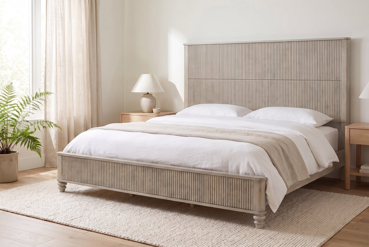 Volterra reeded bed in beige made up with white linen, in a bright bedroom with a fern