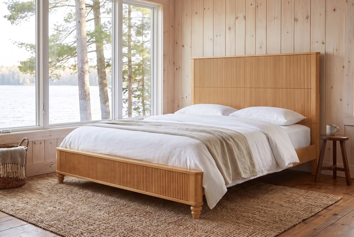Volterra reeded bed in natural in a pine-panelled lakeside cottage bedroom with a jute rug