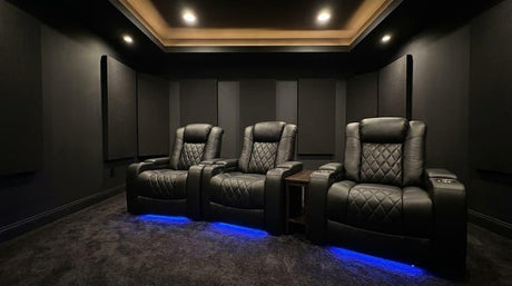 Dark dedicated home theater room with leather recliners, acoustic wall panels, and ambient lighting