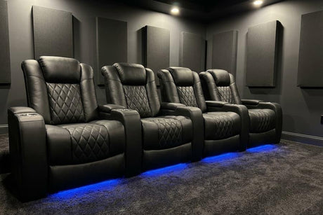 Row of four dark leather cinema recliners with blue LED base lighting in a theater room