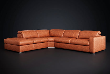 The Clara sectional against a dark studio backdrop, headrests down, the chaise on the left. Shown in distressed full-aniline leather, Tuscan Cognac, Left bumper.