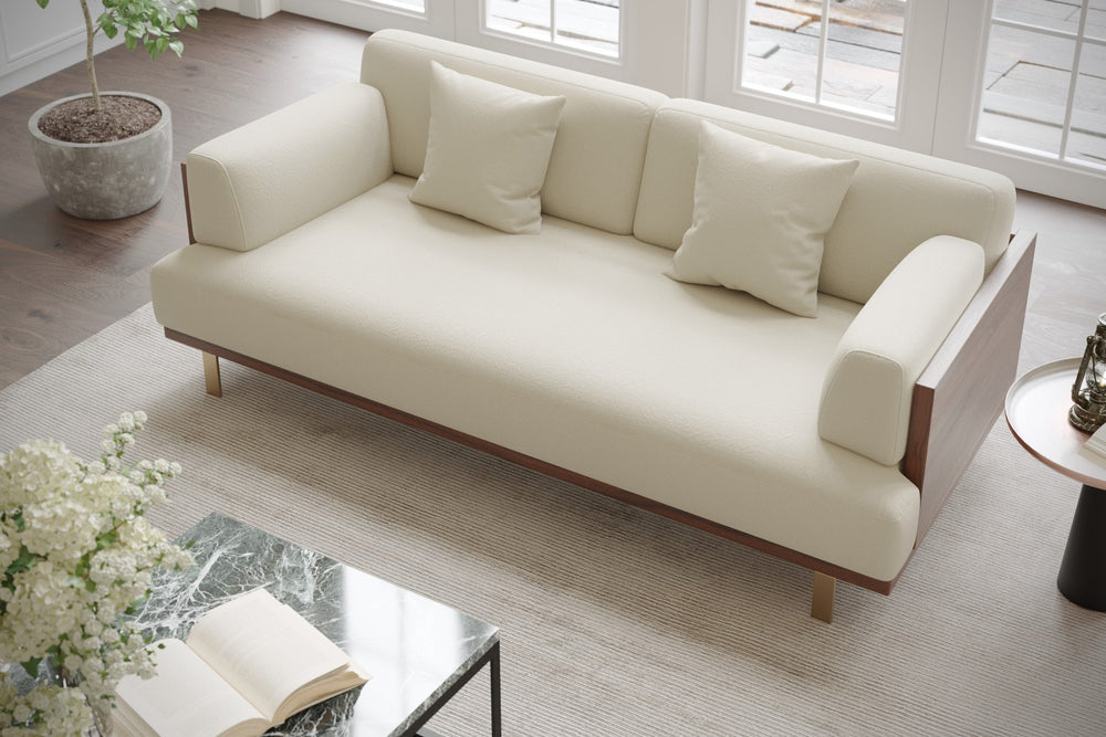 In a Living Room, There is Right Acute Angle Front Top View of A Luxurious, Beige, Kiln Dried Wood Frame, Emilia Modern Fabric Sofa with Two Cushions on It.