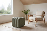 Abbadia ottoman in moss on an oatmeal wool rug beside an oak lounge chair with linen cushions in a Vancouver living room