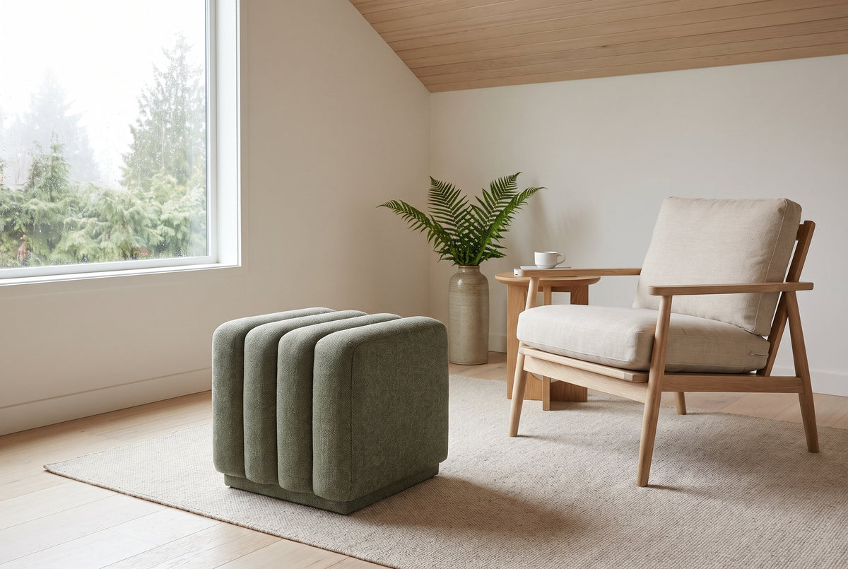 Abbadia ottoman in moss on an oatmeal wool rug beside an oak lounge chair with linen cushions in a Vancouver living room