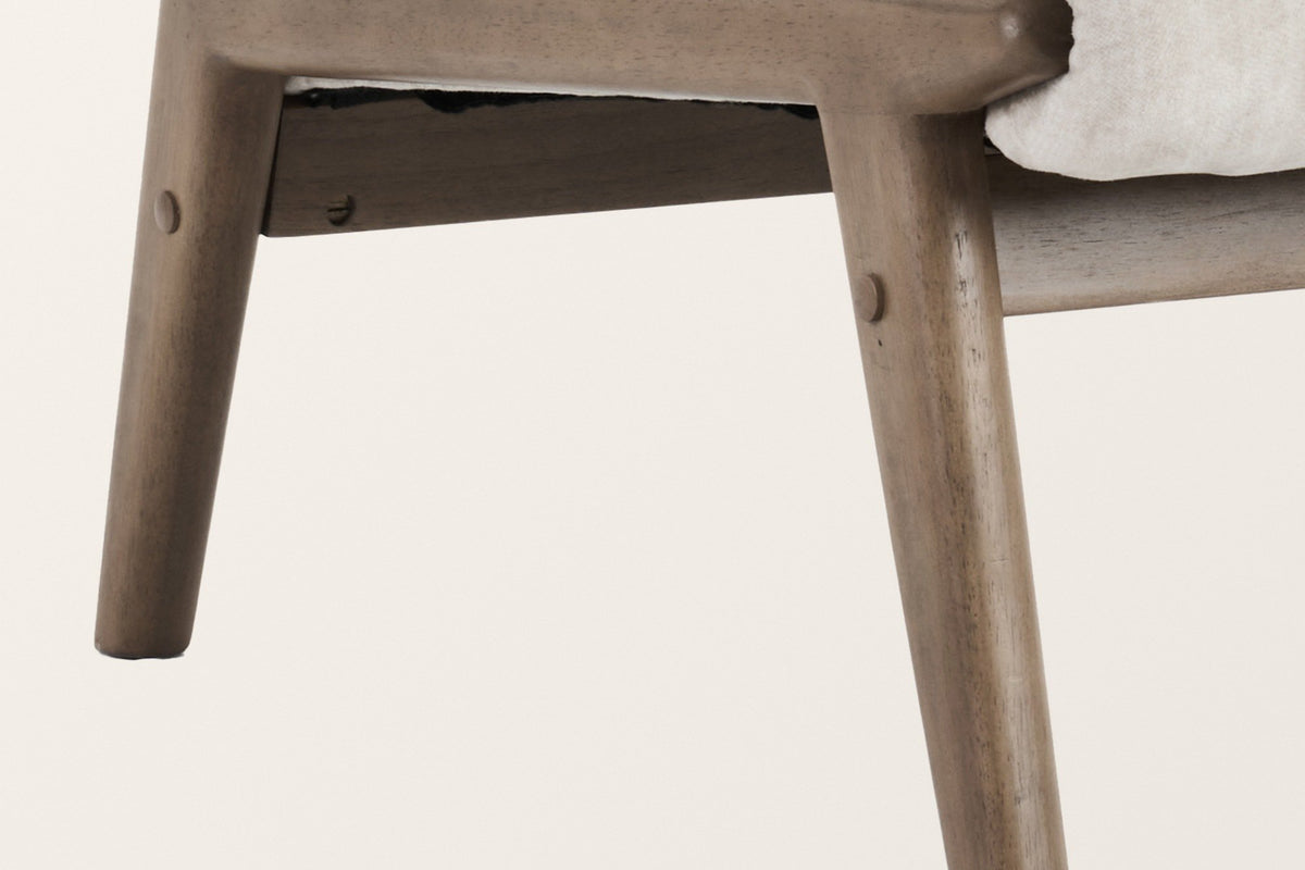 Close-up of the Acquasparta in beige: the walnut-finish side rail, a splayed leg with its dowel peg