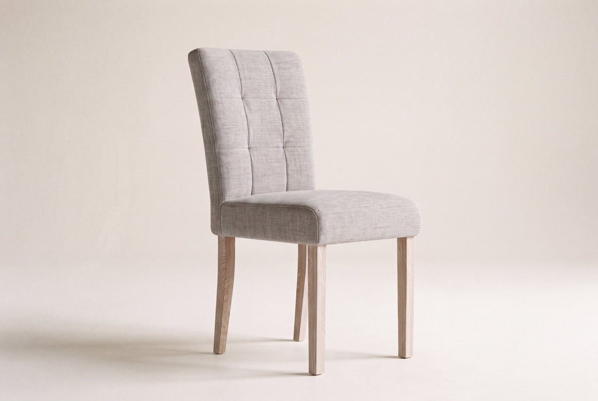 Adelina upholstered dining chair in light grey woven fabric with square pale oak legs on a studio backdrop
