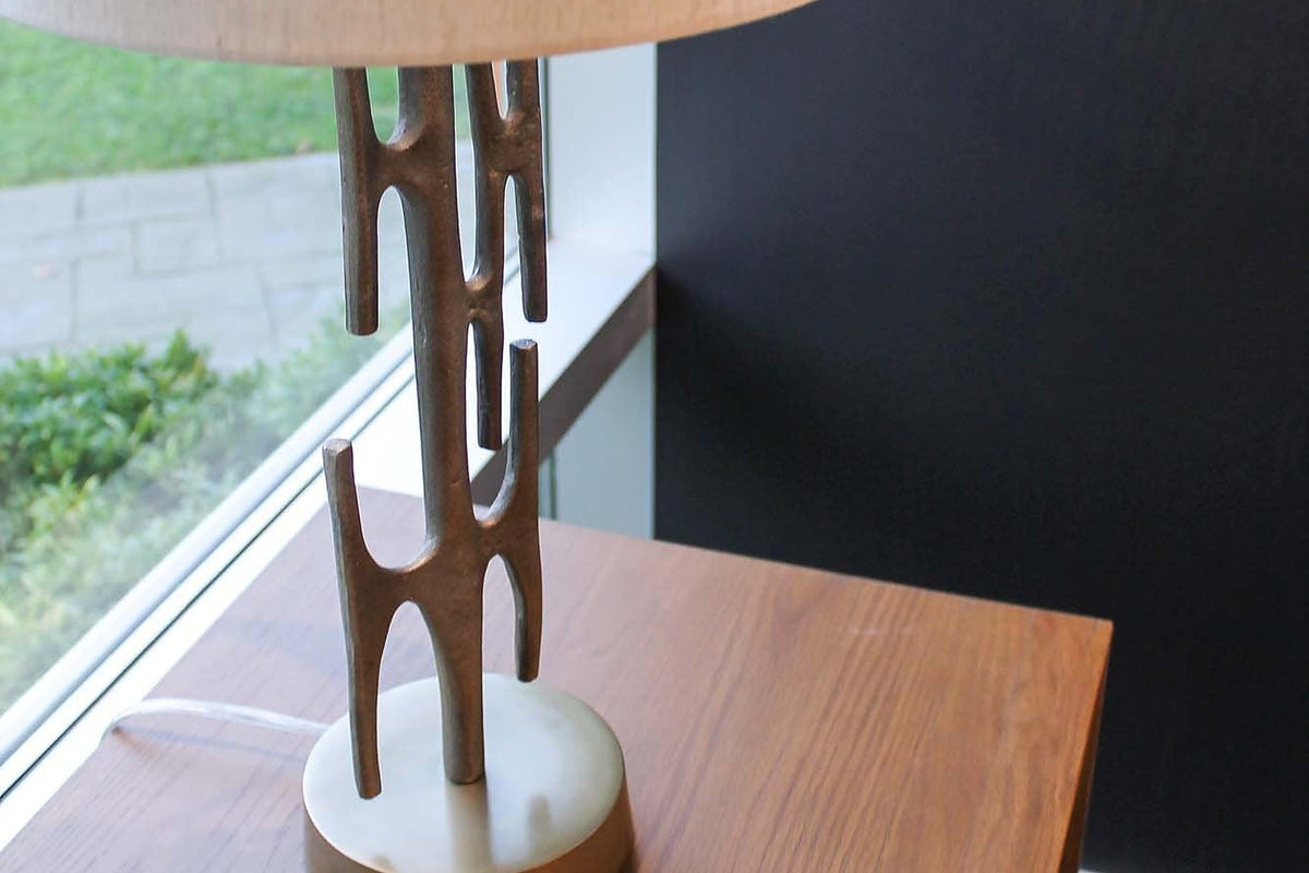 Adeline lamp on a wood side table by a window, showing its branching brass stem