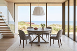 Aggius round dining table in a Cavendish dune house in PEI, with tall glass to the dunes, red cliffs and the Gulf