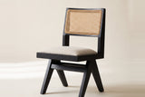 Close-up of the Alaya dining chair cane back panel in its black oak frame and the oatmeal padded seat on an off-white backdrop