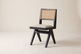 Alaya black oak dining chair with a cane back and oatmeal seat in three-quarter side view on an off-white studio backdrop