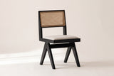 Alaya black oak dining chair with a natural cane back on an off-white studio backdrop