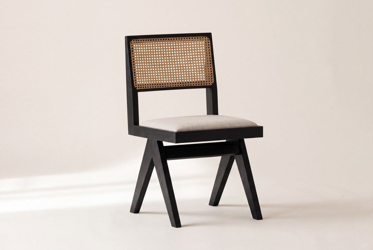 Alaya black oak dining chair with a natural cane back on an off-white studio backdrop