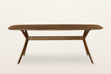 Amandola dining table in Light Walnut, straight front view on a warm white studio backdrop: a long rounded top on crossed leg
