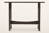 Amelia console table in mocha, straight front view: a thin top on two slotted trestles joined by a curved stretcher