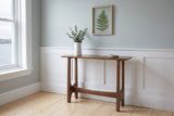 Amelia console table in walnut against a pale grey-blue wall above white wainscot in a Halifax row house front hall