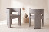 Two Andrea dining chairs, front and back views, beside a travertine side table