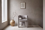 Andrea dining chair against a warm grey plaster wall in a gallery hallway