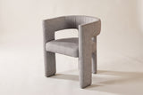 Andrea light grey woven fabric dining chair in three-quarter side view on an off-white studio backdrop