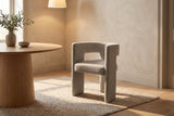 Andrea light grey woven fabric dining chair beside a round oak pedestal table under a linen pendant in warm evening light