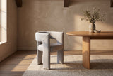 Andrea light grey woven fabric dining chair beside an oval oak table in a room with timber ceiling beams