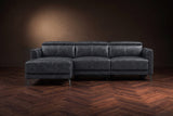 The Andria distressed leather reclining sectional seen from the front on a walnut herringbone floor, headrests down and the footrest closed. Shown in Aged Slate, Left chaise.