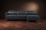The Andria distressed leather reclining sectional seen from the front on a walnut herringbone floor, headrests down and the footrest closed. Shown in Aged Slate, Right chaise.