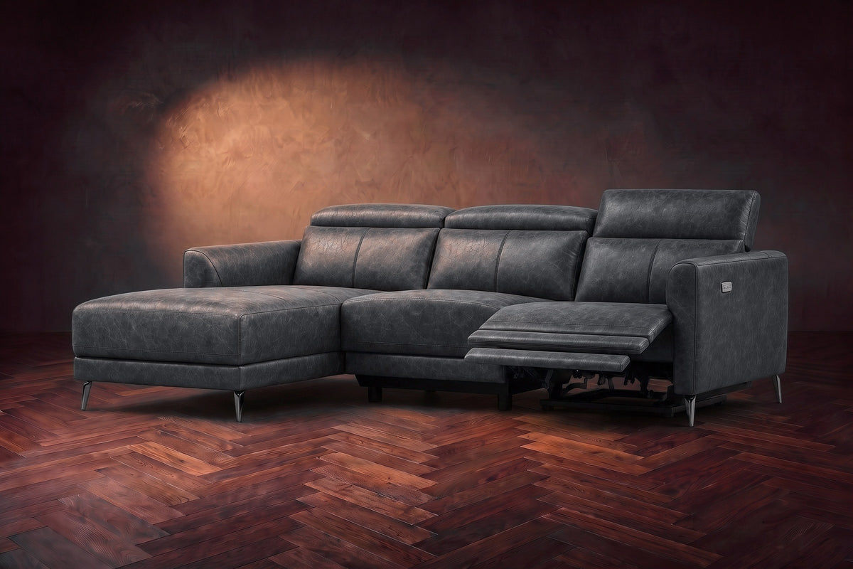 The Andria power reclining sectional on a walnut herringbone floor with the arm-end power recliner open: its two-tier footrest out and its headrest raised. Shown in Aged Slate, Left chaise.