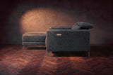 The Andria distressed leather sectional seen from its box-arm end, the chaise reaching forward, on a walnut herringbone floor. Shown in Aged Slate, Left chaise.