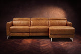 The Andria distressed leather reclining sectional seen from the front on a walnut herringbone floor, headrests down and the footrest closed. Shown in Antiqued Caramel, Right chaise.