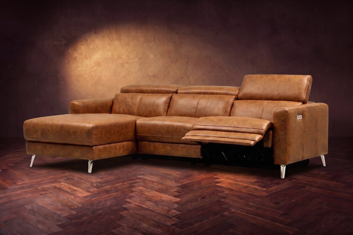 The Andria power reclining sectional on a walnut herringbone floor with the arm-end power recliner open: its two-tier footrest out and its headrest raised. Shown in Antiqued Caramel, Left chaise.