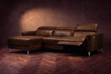 The Andria power reclining sectional on a walnut herringbone floor with the arm-end power recliner open: its two-tier footrest out and its headrest raised. Shown in Burnished Chestnut, Left chaise.