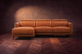 The Andria distressed leather reclining sectional seen from the front on a walnut herringbone floor, headrests down and the footrest closed. Shown in Tuscan Cognac, Left chaise.