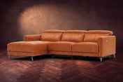 The Andria distressed Italian leather power reclining sectional on a walnut herringbone floor against a brown plaster wall, three-quarter view, headrests down and the footrest closed. Shown in Tuscan Cognac, Left chaise.