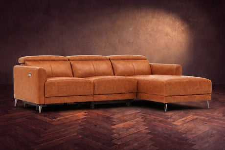 The Andria distressed Italian leather power reclining sectional on a walnut herringbone floor against a brown plaster wall, three-quarter view, headrests down and the footrest closed. Shown in Tuscan Cognac, Right chaise.